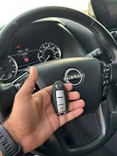Nissan Car Key Replacement Dubai | Car Locksmith Dubai Nissan smart key replacement Dubai โ technician holding new Nissan Intelligent Key inside vehicle