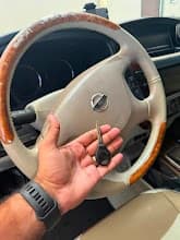 Car Key Duplication Dubai — Car Locksmith Dubai Car key duplication Dubai — technician holding duplicated Nissan transponder key inside vehicle